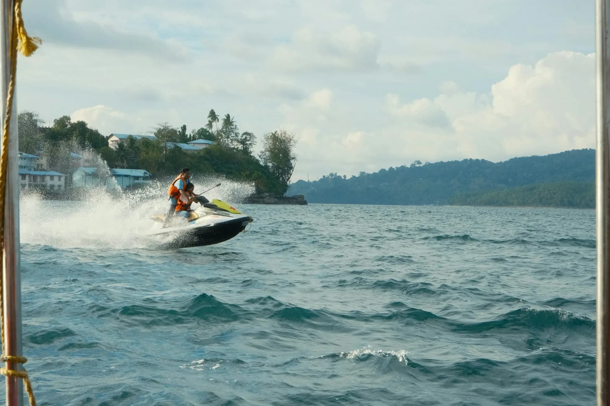 Two riders on a jet ski kicking up spray