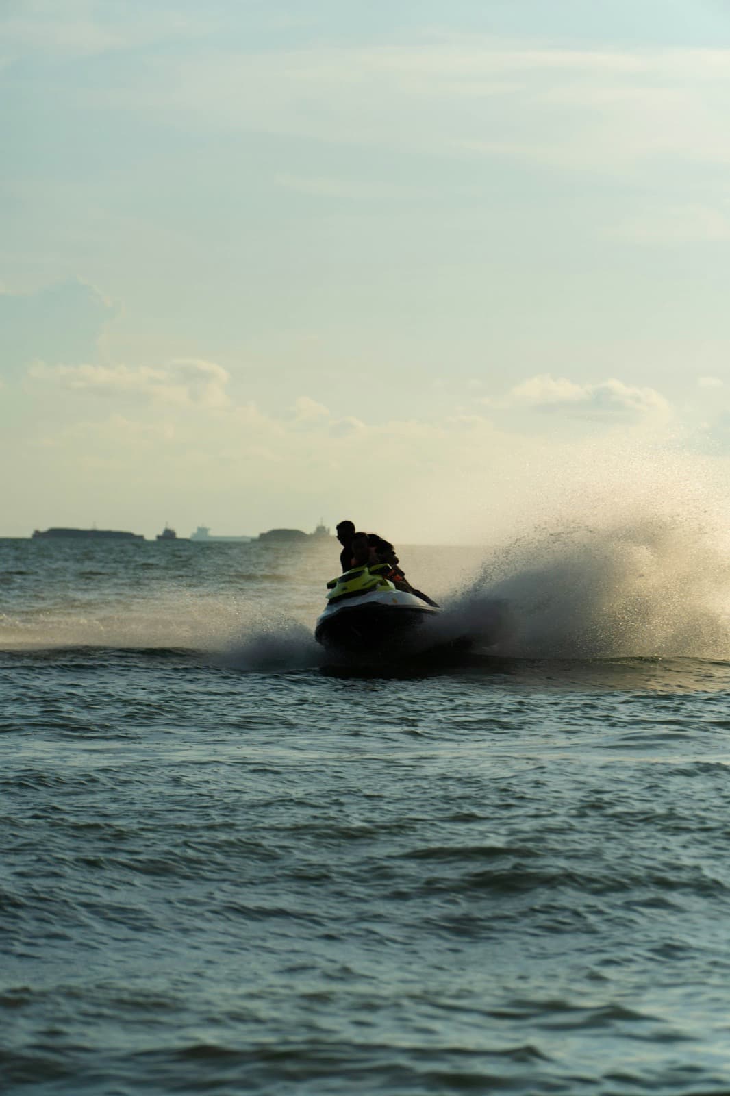 Two people riding a jet ski and kicking up spray